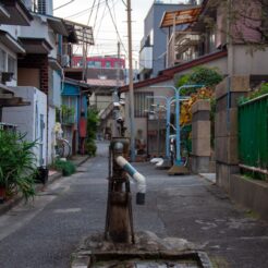 2012-01-15-15-08-28品川宿の路地裏の井戸と後ろを通過する京急電車<br>東品川から泉岳寺を巡り、品川神社や品川宿の裏路地を眺めながら東品川・天王洲を歩く