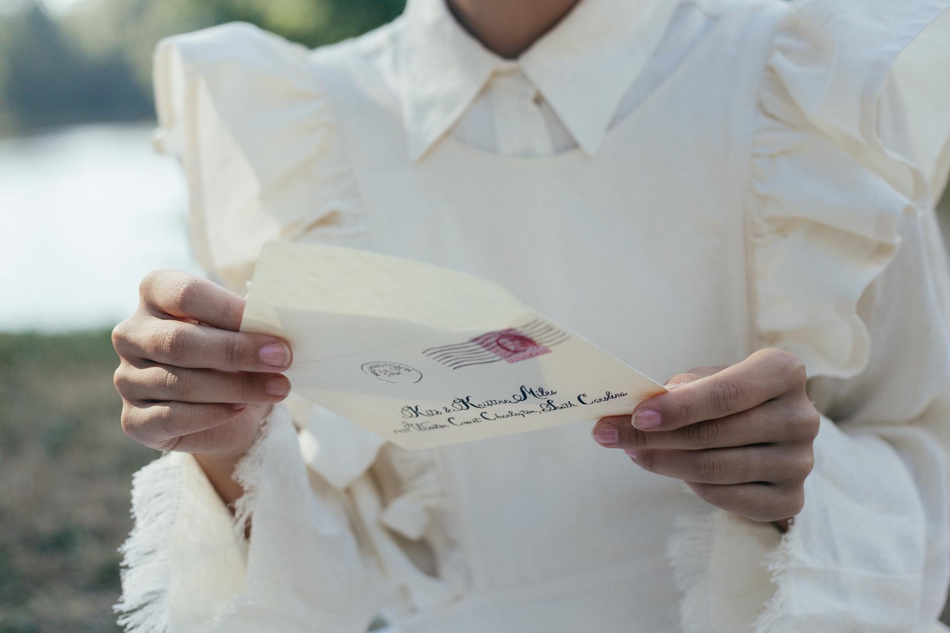 mid section of woman in white dress holding letter