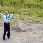 2012-08-13-12-17-58荒廃した鵜住居地区に立って訪れた人に向かって感謝と書かれたボードを掲げる語り部の方