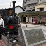 2015-07-05-09-45 道後温泉駅前で坊っちゃん列車と立つCOTA